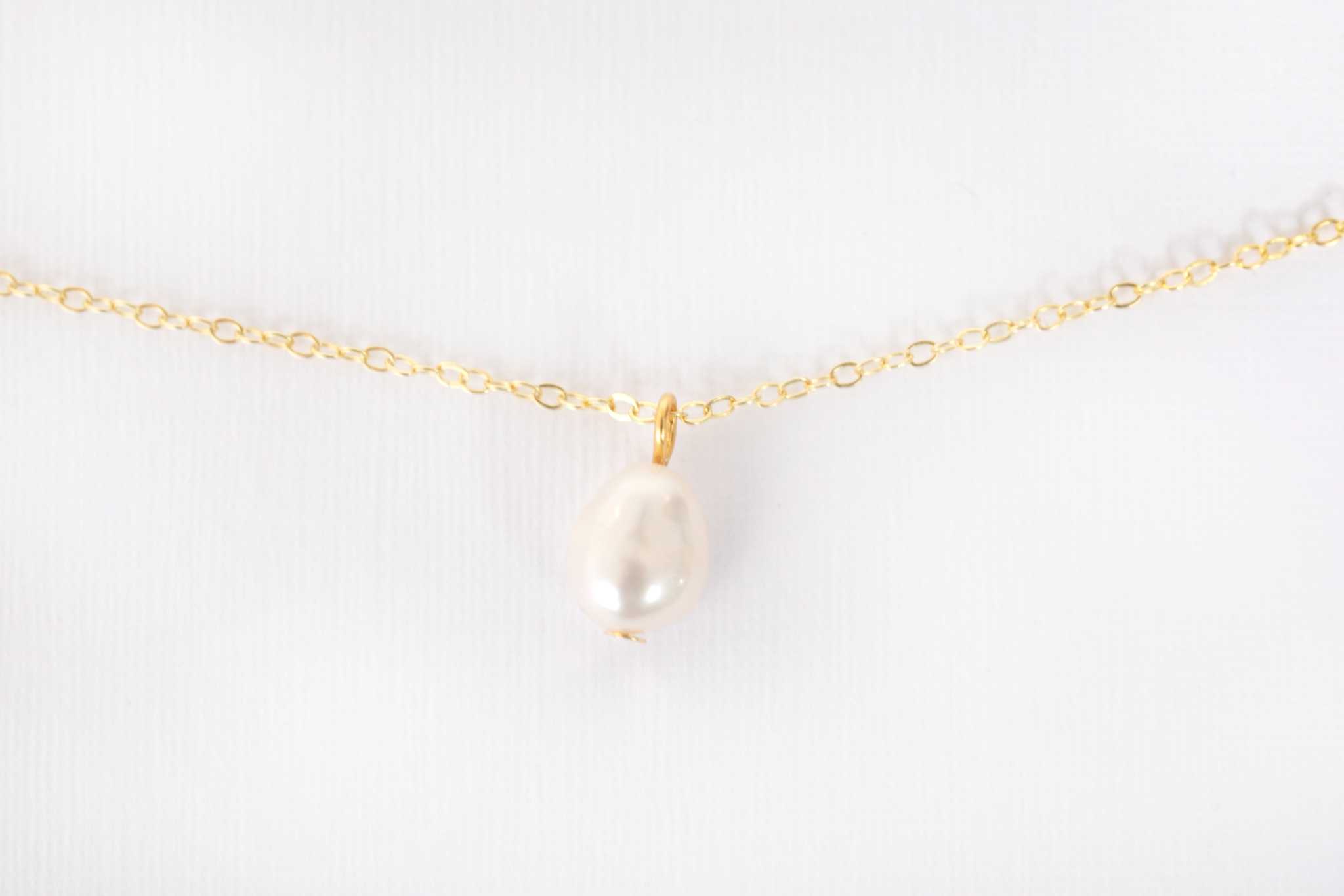 Elisette Pearl Choker displayed on soft fabric showing natural pearl luster and gold accents