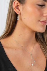 Woman wearing Lucky Bloom freshwater pearl earrings with delicate gold-plated floral detail