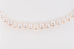 Flat lay of Royale Pearlisma Pearl Necklace with round AAA freshwater pearls and sterling silver clasp