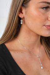 Woman wearing Lucky Bloom freshwater pearl earrings with delicate gold-plated floral detail