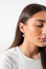 Woman wearing Lilith Pearl Drop Earrings featuring gold plated sterling silver and pearl drop design
