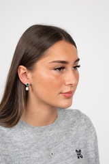 Model wearing Majestic Green Pearl earrings with green jewel and pearl drops