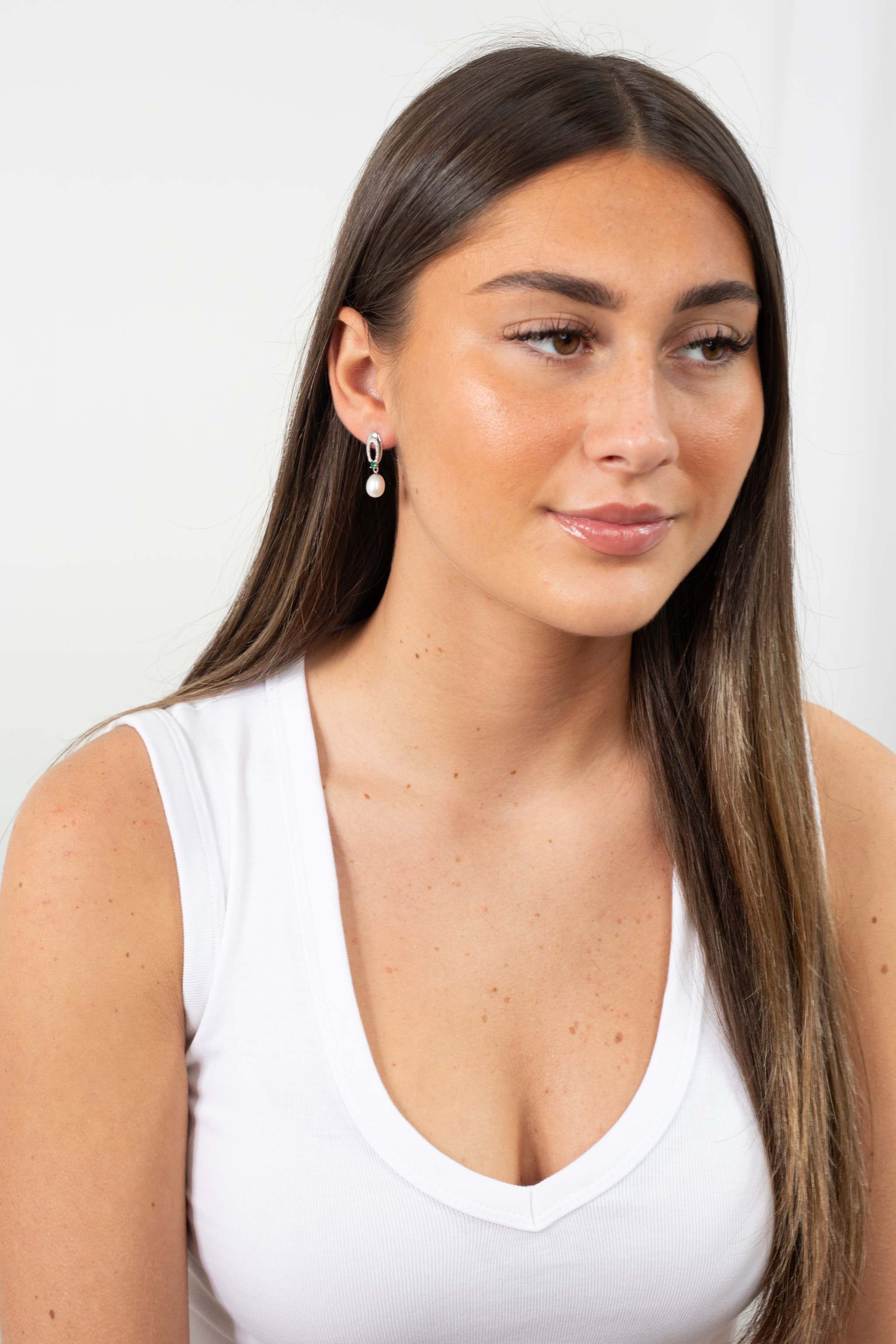 Detailed view of Enigma Pearl Earrings with natural freshwater pearls and emerald stones